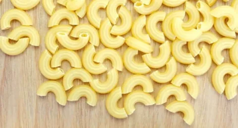 Macaroni noodles scaattered on a wooden background