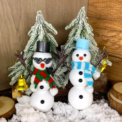 Two clay snowmen in front of flocked trees