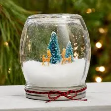 A picture of a glass ball, containing two faux miniature deer and a tiny tree. the items in the ball are covered in artificial snow.